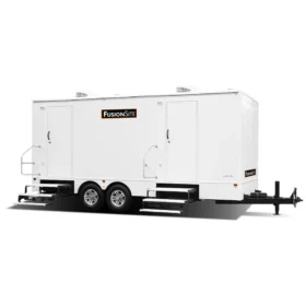 A white FusionSite restroom trailer with two entry doors, metal handrails, and dual steps is designed for event or job site sanitation.
